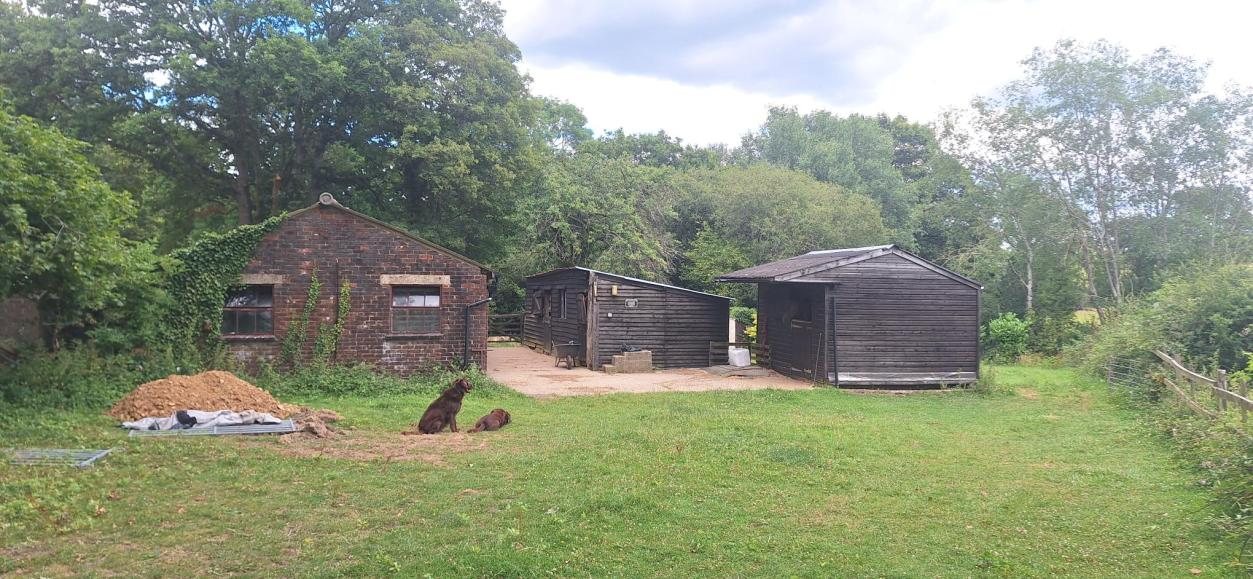 The existing agricultural barn at the farm near Pulborough with the trial pit spoil in the foreground